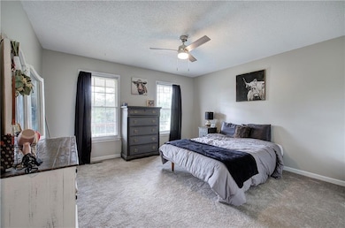 Carpeted bedroom featuring a textured ceiling, bas