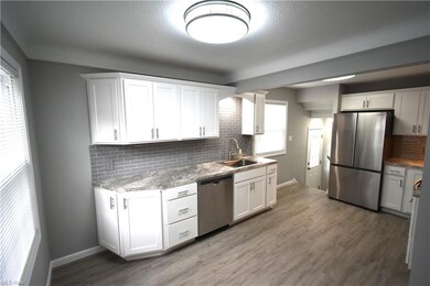 Another View of spacious Kitchen with backsplash, white cabinets, light countertops, appliances with stainless steel finishes, and Vinyl Planking Flooring