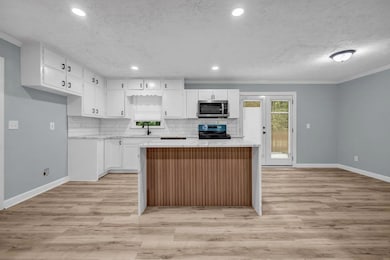 Kitchen featuring crown molding, appliances with stainless steel finishes, recessed lighting, baseboards, and light wood-type flooring