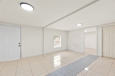 The open-concept living area seamlessly transitions into the bedroom, unified by sleek tile flooring—an ideal layout for maximizing space and rental appeal.