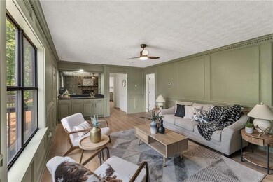 Living room featuring a decorative wall, light wood-style floors, a textured ceiling, ceiling fan, and ornamental molding