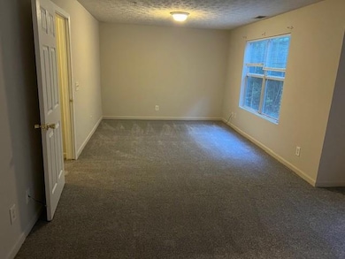 Spare room with dark carpet and a textured ceiling