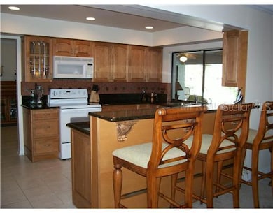 Kitchen - Spacious kitchen features granite counter tops with tile backsplash, recessed lighting and solid maple wood cabinetry. Large pass-thru window looks out over pool and lanai.