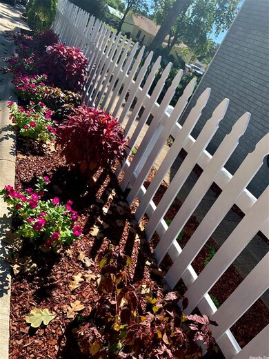 flowers peek from picket fenced cobblestone path