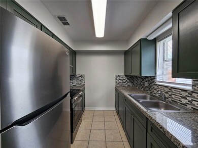Kitchen with stainless steel appliances, a sink, decorative backsplash, and dark countertops