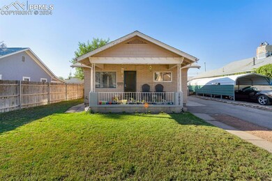 Bungalow-style home with a front yard, covered porch, and a carport
