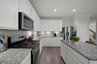 Kitchen featuring decorative backsplash, light wood-style flooring, ornamental molding, stainless steel appliances, and a kitchen island