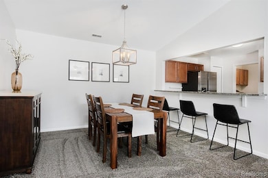 Dining space featuring dark colored carpet, lofted ceiling, and a chandelier