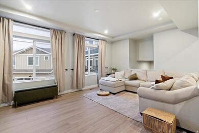 Living area with light wood-type flooring, a raised ceiling, and recessed lighting