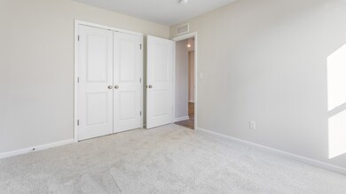 Carpeted secondary bedroom with double door closet in a DRB Homes Cranberry plan at the Village of College Park community.