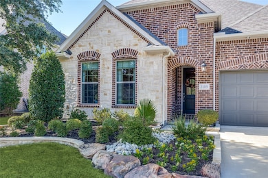 View of front facade with stone siding, brick siding, roof with shingles, and an attached garage