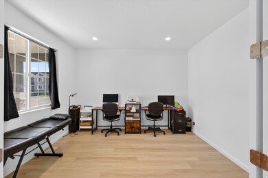 Home office with light wood finished floors and recessed lighting