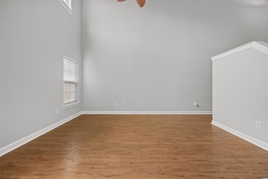 Unfurnished room with a high ceiling, wood finished floors, and a ceiling fan