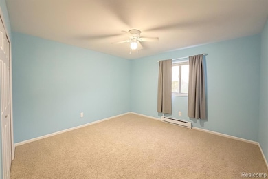 Spare room with carpet flooring, a baseboard heating unit, and a ceiling fan
