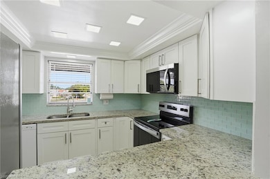 LIGHT AND BRIGHT UPDATED KITCHEN WITH SLEEK WHITE CABINETRY, GRANITE COUNTERS, AND TRAYED CEILING WITH RECESSED LIGHTING..