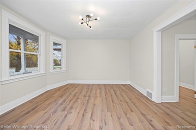 Spare room featuring a chandelier and light wood finished floors