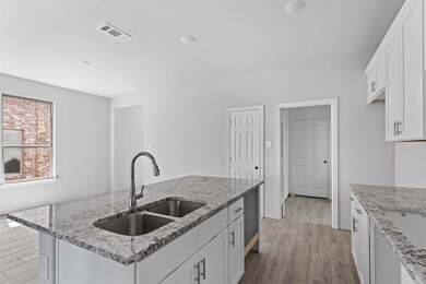 Kitchen with sink, white cabinetry, light stone co