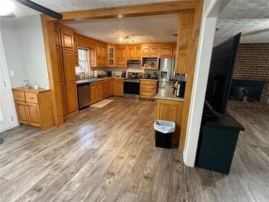 Kitchen featuring brown cabinets, a textured ceiling, light wood finished floors, appliances with stainless steel finishes, and light countertops