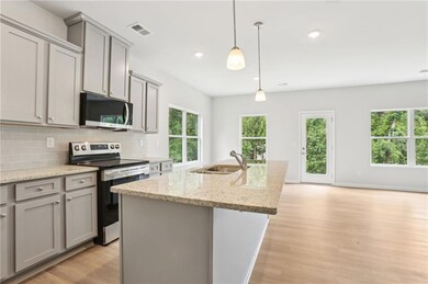 Kitchen featuring stainless steel appliances, gray cabinets, a sink, light wood finished floors, and recessed lighting