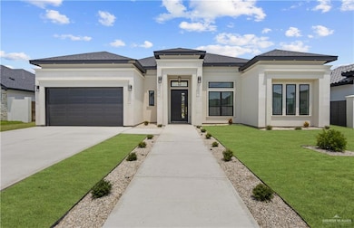 Prairie-style home featuring a garage, driveway, a front lawn, stucco siding, and roof with shingles