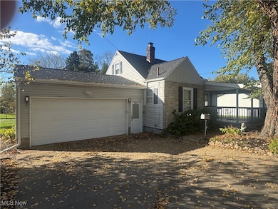 View of front of property with a chimney, driveway, an attached garage, and stone siding