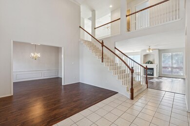 Entryway with hardwood / wood-style floors, a high ceiling, and ceiling fan with notable chandelier