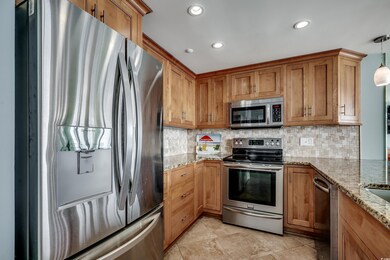 Kitchen with stainless steel appliances, backsplash, brown cabinetry, and recessed lighting