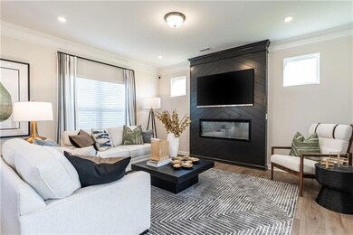 Living area featuring ornamental molding, healthy amount of natural light, a fireplace, light wood-style floors, and baseboards