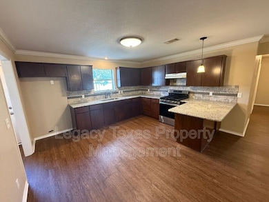 Kitchen featuring dark brown cabinetry, ornamental molding, decorative backsplash, gas stove, and light stone counters