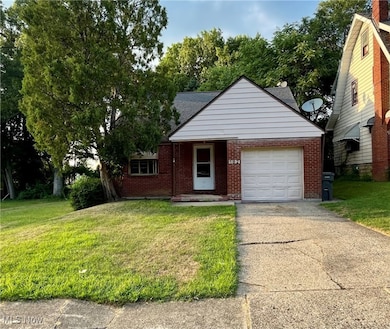 View of front facade featuring an attached garage, concrete driveway, a front lawn, and brick siding