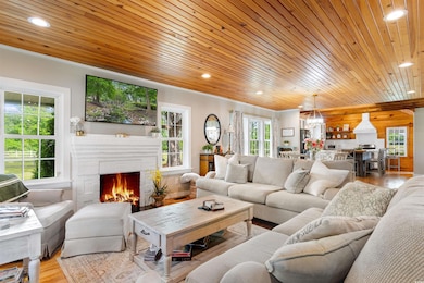 Living area featuring wooden ceiling, a warm lit fireplace, recessed lighting, and wood finished floors