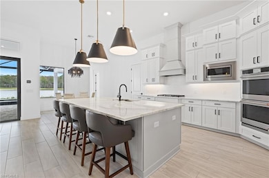 Kitchen featuring appliances with stainless steel finishes, tasteful backsplash, an island with sink, a kitchen breakfast bar, and white cabinetry