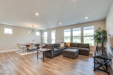 Living room featuring healthy amount of natural light, light wood-style floors, recessed lighting, a textured ceiling, and a chandelier