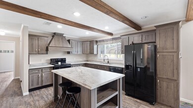 Kitchen with black fridge, custom exhaust hood, beam ceiling, crown molding, and open shelves