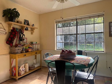 Dining area featuring plenty of natural light, light tile patterned floors, a textured ceiling, wainscoting, and ceiling fan