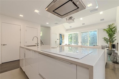 Kitchen featuring white electric stovetop, a sink, light wood-style floors, white cabinetry, and light countertops