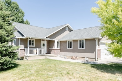 View of front of home featuring stucco siding, covered porch, a garage, and a front yard