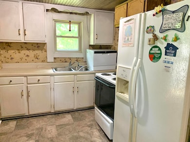Kitchen with white appliances, a sink, light countertops, and white cabinetry