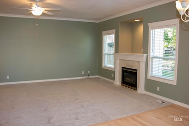 Unfurnished living room with crown molding, a fireplace, light wood-type flooring, a ceiling fan, and a textured ceiling