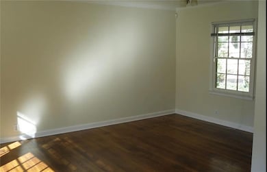 Empty room featuring dark wood-style flooring and baseboards