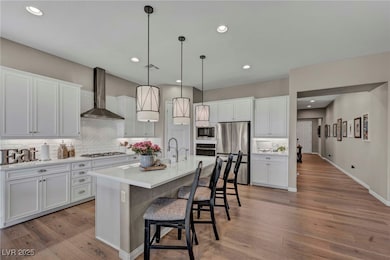 Kitchen featuring wall chimney range hood, light w