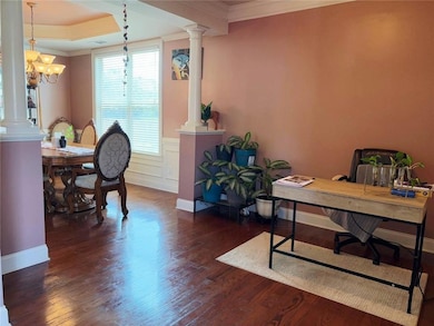Office space featuring ornate columns, ornamental molding, dark wood finished floors, a chandelier, and wainscoting