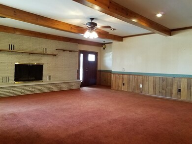 The existing family room with fireplace, wood beams, and separate entrance.