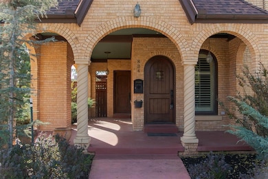 View of exterior entry featuring brick siding, a porch, and a shingled roof