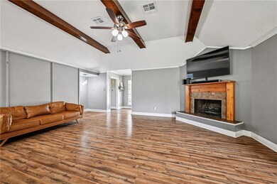 Open and inviting living room with vaulted ceilings, exposed wood beams, cozy fireplace, and abundant natural light.