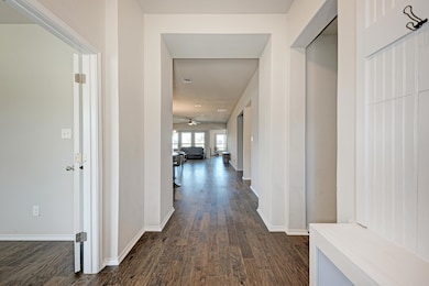 Hall featuring dark wood-style flooring and baseb