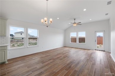 Unfurnished living room with a ceiling fan, wood finished floors, a chandelier, recessed lighting, and lofted ceiling