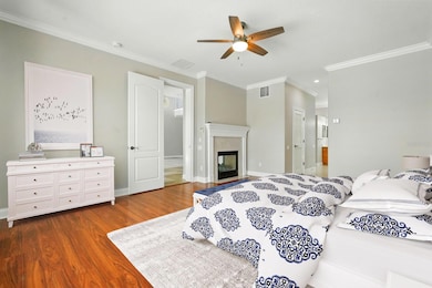 Spacious primary ensuite featuring a cozy fireplace, elegant wood floors, and direct access to the pool for the ultimate retreat.