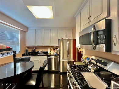 Kitchen with stainless steel appliances, white cabinets, and dark countertops