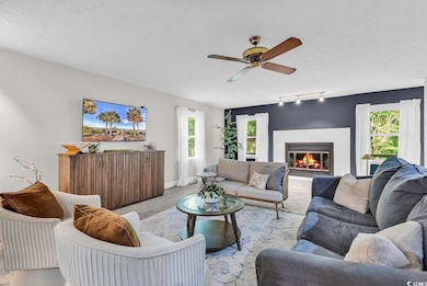 Carpeted living room with a textured ceiling, a ceiling fan, a glass covered fireplace, track lighting, and baseboards